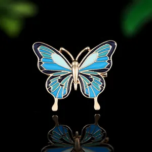 Gros plan d'un pin's papillon en émail bleu et doré avec des motifs d'ailes détaillés
