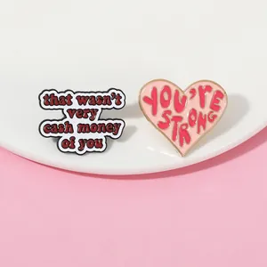 Macro shot of zinc alloy enamel pins with That wasn't very cash money and You're strong text