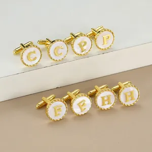 Close-up of gold men's cufflinks with mother of pearl inlay and engraved alphabet initials