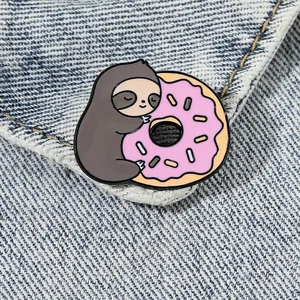 Broche en émail mignonne avec paresseux et donut rose sur fond de veste en jean bleue