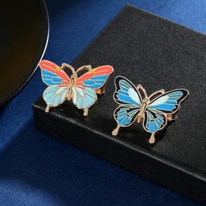 Détail macro de deux broches papillon colorées en émail sur un présentoir noir luxueux