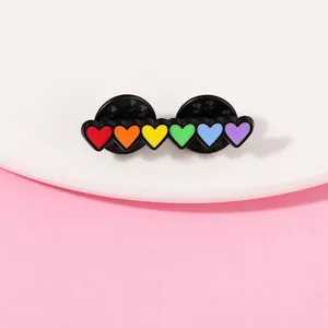 Close-up of rainbow heart enamel pin with double black rubber clutches and metal backing