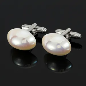 Détail de boutons de manchette argentés avec perle ovale et reflets irisés roses
