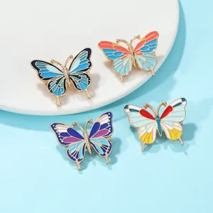 Lot de quatre pin's papillon en émail coloré avec bords dorés sur socle blanc