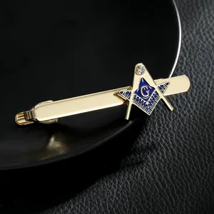 Detailopname van gouden vrijmetselaars dasclip met blauw emaille G-logo en zirkoon