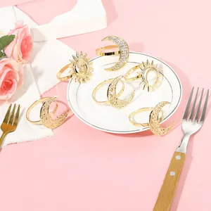 Detail of golden moon and sun napkin rings set on white table setting with pink roses