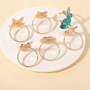 Set of 6 golden rabbit napkin rings with green enamel finish on white ceramic plate