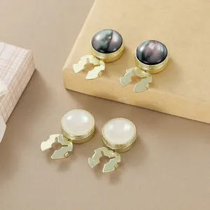 Close-up of golden round cufflinks with dark and white iridescent pearl inlay