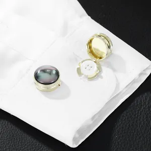Gold-plated cufflinks with abalone shell inlays on white shirt cuffs and black leather