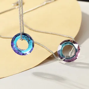 Close-up of multifaceted crystal pendants on box chains with blue and pink gradients