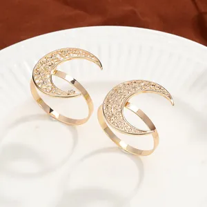 Detailed view of hollow gold moon napkin rings with stars on a white plate