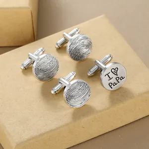 Detailed view of silver cufflinks featuring finger print texture and I Love Papa engraving
