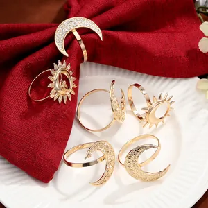 Detailed close-up of golden sun and moon napkin rings on a red cloth napkin