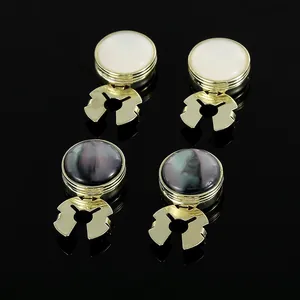 Macro detail of gold-plated cufflinks with white and dark shell inlays on black mirror