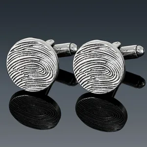 Close-up of vintage silver cufflinks with industrial fingerprint texture and reflection