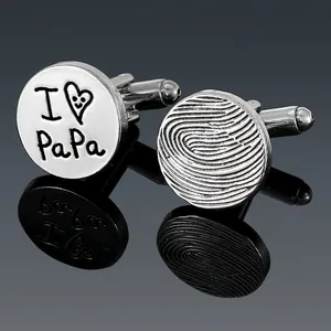 Macro shot of silver round cufflinks with I Love Papa text and fingerprint pattern
