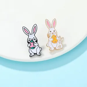Detalle de dos pines esmaltados de conejos de Pascua con huevos sobre un plato blanco