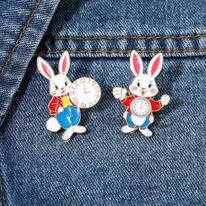 Detalle de dos broches de conejo esmaltados con diseño de reloj sobre tela vaquera