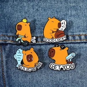 Vue détaillée de quatre jolies épingles en émail capybara sur fond de tissu denim bleu
