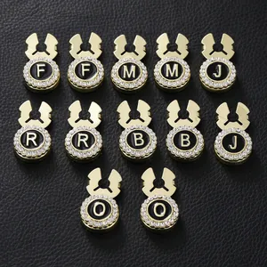 Close-up of gold-plated alphabet charms with black enamel and rhinestones on black leather
