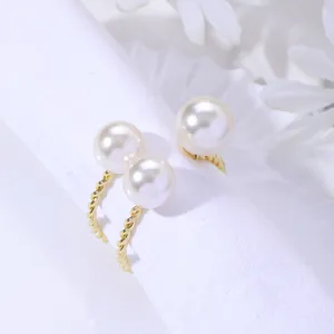 Gros plan de boucles d'oreilles dorées torsadées avec de grandes perles blanches