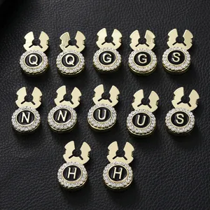 Detailed close-up of 12 gold plated letter cufflinks with rhinestones on black leather