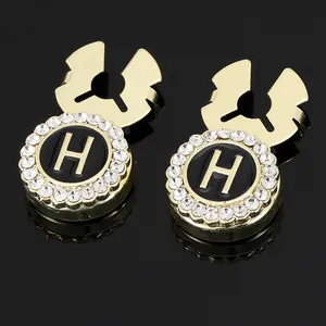 Detail shot of gold-plated cufflinks featuring black enamel H logo and sparkling crystals