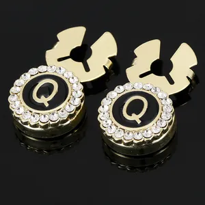 Detailed macro of gold letter Q cufflinks with black enamel and sparkling rhinestones