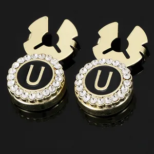 Detail of gold letter U cufflinks with black enamel and rhinestones on black background