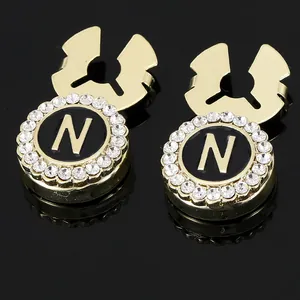 Macro detail of gold-plated cufflinks with letter N, black inlay, and sparkling zircons