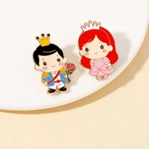Detailansicht der Prinz und Prinzessin Emaille-Pins am Rand eines weißen Tellers