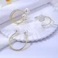 Ronds de serviette dorés avec perles blanches sur un support blanc minimaliste