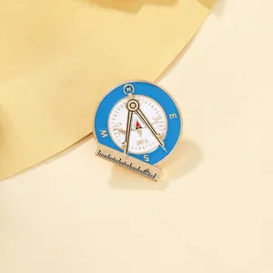 Detail of vintage architect enamel brooch featuring a blue compass and golden calipers