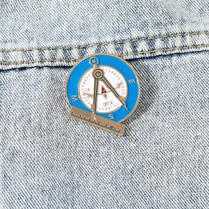 Vintage round enamel compass brooch with nautical tools on blue denim fabric background