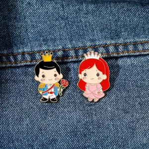 Nahaufnahme süßer Emaille-Anstecknadeln von Prinz und Prinzessin auf Denim-Stoff