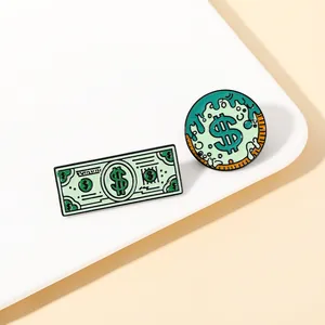 Close-up of two green enamel pins featuring a banknote and a dollar sign on white stand