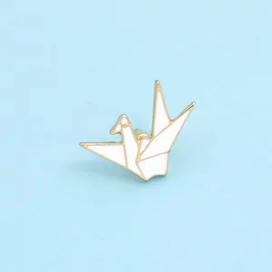 Detailed close-up of a white and gold origami crane brooch with enamel finish