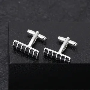 Macro detail of silver-tone cufflinks with black enamel inlay on dark textured background