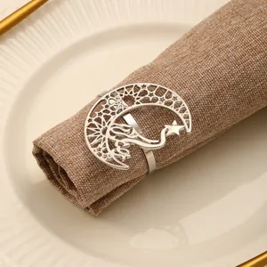 Close-up of silver hollowed moon and star napkin ring on a beige dinner plate