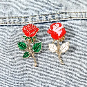 Elegante Emaille-Anstecknadeln in Rosenform in Rot und Rosa auf Denim-Hintergrund
