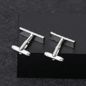 Polished silver rectangular cufflinks with engraved textures on a dark display box