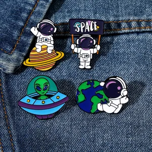 Macro shot of 4 space enamel pins on denim, showing astronaut and alien badge details