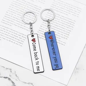 Detail view of dual rectangle couple keychains with enamel engraving on book background