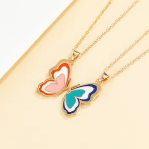 Detailed close-up of butterfly wing pendants in colorful enamel with gold chains