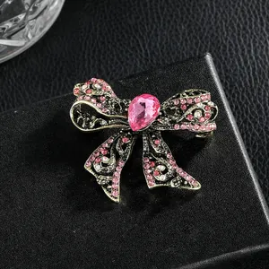 Elegant vintage gold bow brooch with pink crystals and pear-shaped gemstone in macro view
