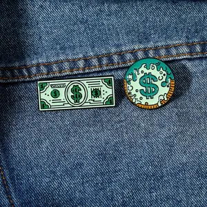 Detail of dollar bill and mint green liquid enamel pins on dark blue denim fabric