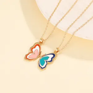 Close-up of golden butterfly pendant necklaces with colorful enamel inlay detail
