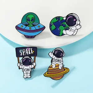 Detailed close-up of four colorful space astronaut and UFO enamel pins on white plate