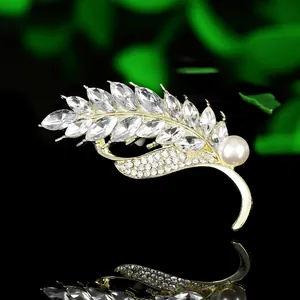 Close-up of golden wheat brooch with sparkling marquise rhinestones and white pearl detail