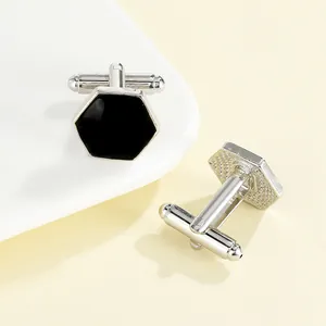 Close-up of polished silver cufflinks with hexagonal black inlay and T-bar swivel back